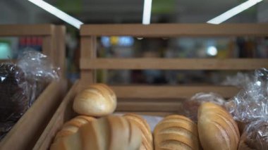 Kadın eli, süpermarkette bir vitrine bir sürü somun ekmek serpiştirilmiş. Yüzü yok.