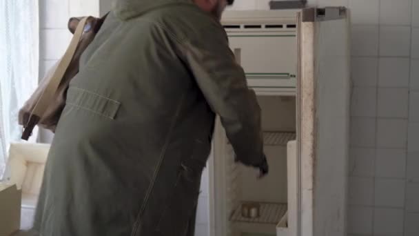 Ένας Βρώμικος Γενειοφόρος Παλιά Ρούχα Ανοίγει Ένα Σκουριασμένο Ψυγείο Και — Αρχείο Βίντεο