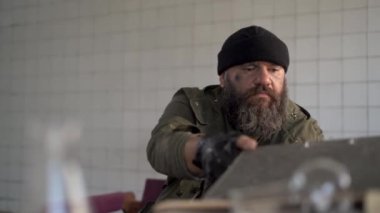Depressed dirty man sitting in an abandoned building after the war reads documents. Post-apocalyptic survivor. Life in a post-apocalyptic world