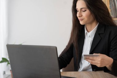 İnternet üzerinden alışveriş yapmak için kredi kartı ve laptop kullanan bir kadın, online alışveriş ödeme kavramı.