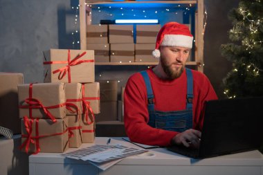 small business owner freelance Santa working in home office using computer, online marketing packaging box and gifts for Christmas delivery, SME e-commerce concept, Christmas sale
