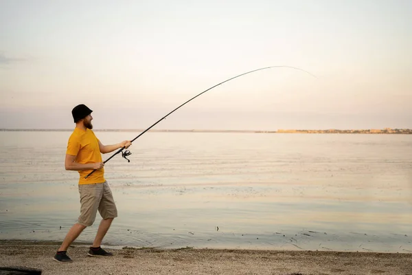 Young man fishing in a pond in a sunny day. fisherman outdoor leisure lifestyle. Free space