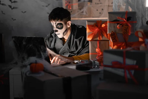 Drop shipping business owner wears white clay skull, professional makeup in home office. accepts an order on the site. Festive decorated office. Halloween sale concept, . copy space