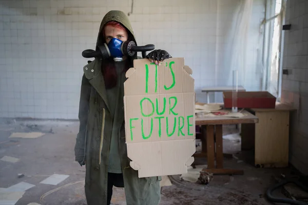 Environmental pollution, ecological disaster, nuclear war, woman in gas mask with a banner that says: it\'s our future. post apocalypse concept. Care for future generations.