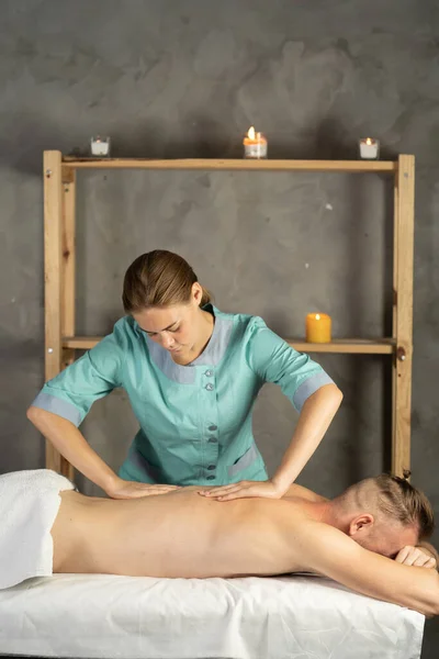 Man receiving massage relax treatment from female hands.mens back massaged by masseuse in spa salon