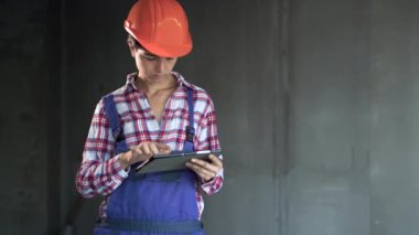 Üretim mühendisliği planı. Consuction sitesinde güvenlik kasketi takan kadın. Dijital tabletli yakışıklı müteahhit süreci. İnşaatçının mesleği kapalı mekanda yakın çekim yapmak.