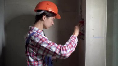 Elektrik mühendisi kadın elektrik paneli diyagramını tabletle çiziyor, elektrik panosunun içine bakıyor, endüstriyel binada onarım ve yenileme yapıyor. İnşaat, elektrik ve teknoloji kavramı