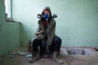 Gaz maskeli, yıkık dökük bir binada oturan kıyamet sonrası hayatta kalanlar. Çevre felaketi. Çevre kirliliği, ekolojik felaket, nükleer savaş, kıyamet sonrası kavramı.