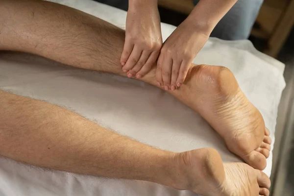 Close up of Female therapist giving leg and calf massage to athlete patient on the bed in clinic for sports physical therapy concept