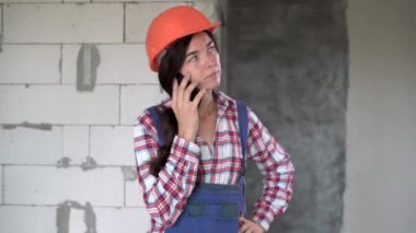 İnşaat ofisindeki akıllı telefondan kasklı kadın müteahhit arıyor. mimari, inşaat işi ve inşaat kavramı
