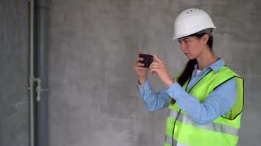 İnşaat alanında akıllı telefon kullanarak fotoğraf çeken kadın inşaat mühendisi. Fotoğraf raporlama yöneticisiName