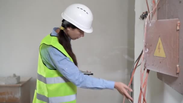 Young Female Electrician Works Tablet Standing Industrial Fuse Board Cabinet — Stock Video