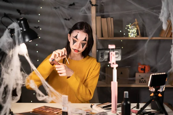 Asia girl beauty blogger does Halloween make up, reviews beauty product for video blog, gives advice to girls and women, films process on camera. Online merchants selling cosmetics. Copy space