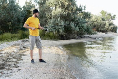 Genç adam gün batımında bir teknede gölde balık tutuyor. Balıkçı açık hava eğlence yaşam tarzı.