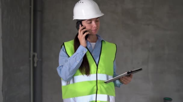 建設現場のコンセプトで働く建設エンジニアや建築家 携帯電話の建設現場にタブレットを持つ女性のフォアマン 建築局 — ストック動画