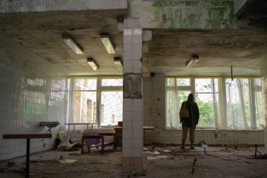 Adam terk edilmiş bir binada duruyor. Gezgin adamlar. Kapüşonlu koruyucu pelerinli bir adam. Kıyametten sonra. Kıyamet sonrası bir dünyada yaya olarak seyahat etmek..