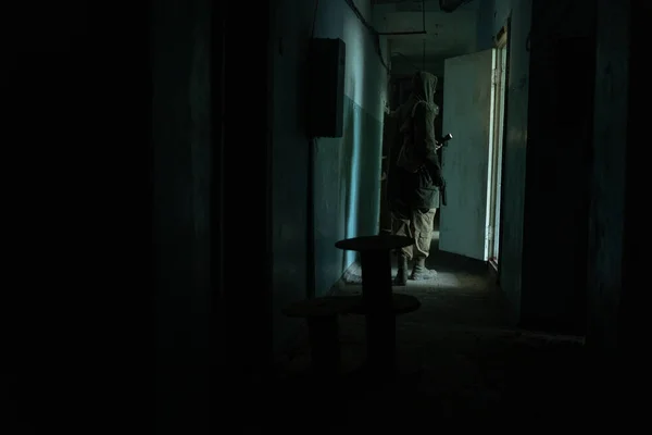 a man walking in a dark corridor of abandoned build, with flashlight in darkness