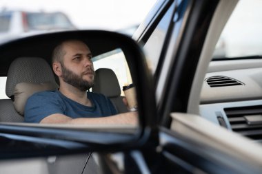 Dikiz aynasından bakan ciddi şoför dönmeden önce şeridin boş olduğundan emin oluyor. İnsan yüzü duygularını ifade eder. Güvenli yolculuk konsepti