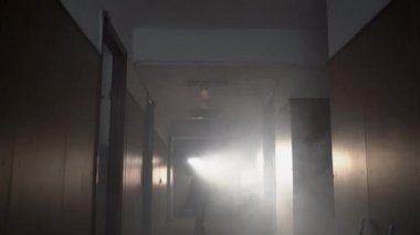 Gaz maskeli ve el feneriyle duman içinde kalmış bir kadın. Gece bir bina, hava kirliliği konsepti.