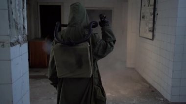Karanlık bir binanın içinden el feneriyle yürüyen, gaz maskeli bir kıyamet gününden kurtulan birinin arka görüntüsü. Radyasyon kirliliği, zehirli çevre. Kıyametten sonraki konsept