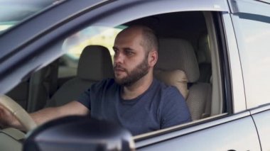 Şoför bey arabayla giderken yemek yiyor. Fast food personeli araba vitrinindeki erkek müşteriye sipariş veriyor.