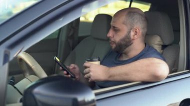 Kafkas sakallı adam kahve içiyor ve arabada cep telefonu kullanıyor. Genç bir erkek cep telefonundan iş e-postalarını kontrol ediyor. Şoför sosyal medyada gezinmek ve kahve içmek için akıllı telefon kullanıyor..