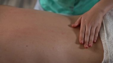 Tanınmayan bir adam masaj yaptırıyor. Rahatlatıcı bir tatil, huzur evi, zevk. Profesyonel masörün elleri erkek müşterinin sırtına masaj yapar.