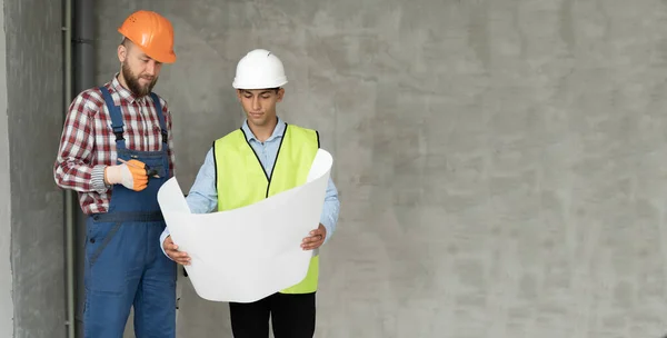 建築家や建設技師や測量士の議論の計画や設計図 2人の男が堅い帽子をかぶっていて 屋内の家の建設現場に立っている バナー — ストック写真