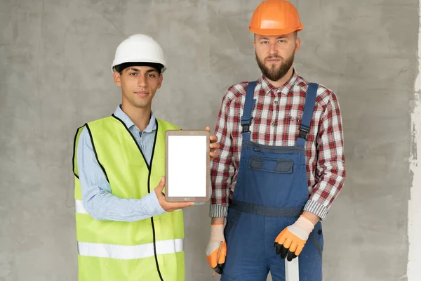 Two business builder people at construction site. Blank screen tablet computer. Builder, inspector, engineer, architect, customer, people working at building concept