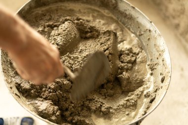 Erkek eli çimento harcı yoğuruyor, malayla, yakın plan. İnşaat işi. Düz ev yenileme kavramı