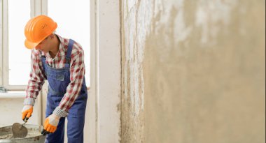 İnşaatçı işçi sıva tutuyor ve eve beton duvar yapıştırmak için mala kullanıyor. İnşaat işi ve tamir konsepti. Pankart