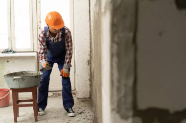 Evdeki beton duvarı alçılamak için mala sıva kullanan insan müteahhiti. inşaat işi ve onarım kavramı