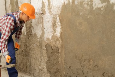 İnşaat alanındaki duvar inşaatında alçı beton işçisi. Ev konseptini onar