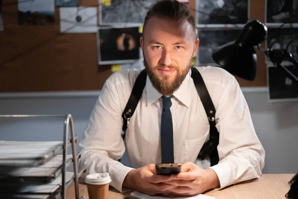 portrait of detective working in office at table with phone, detective concept