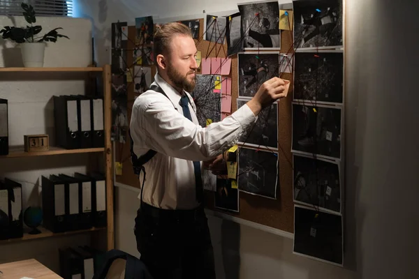 Detective looking at evidence board in office, clue and blueprints on mud board of investigator, private detective agency concept