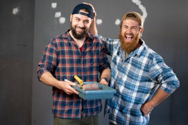 Boyacı aletleriyle iki neşeli zanaatkarın komik portresi. ev yenileme ve duvar boyama konsepti