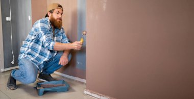 Oda boyama işi. Beyaz, sakallı, paten boyalı bir oda boyacısı. Pankart