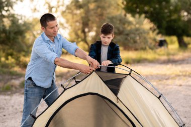 Baba oğlunun yaz ormanı açıklığında kamp çadırı kurduğunu öğrendi. Kamp insanları açık hava yaşam tarzı konsepti