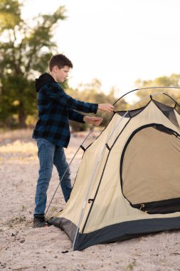 Sevimli çocuk ergen oğlu çadır kuruyor. Çocukların doğal eğitimi. Yaşam tarzı turistler. Boşluğu kopyala
