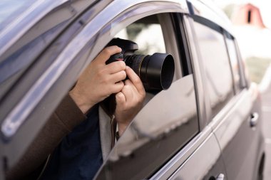 Arabasında otururken sokakta fotoğraf çeken özel dedektif, müfettiş ya da paparazzi.