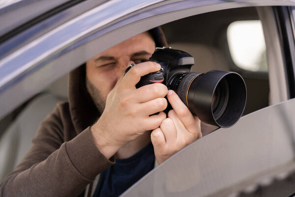 Male driver photographing with slr camera from car, Private detective taking photos, close up