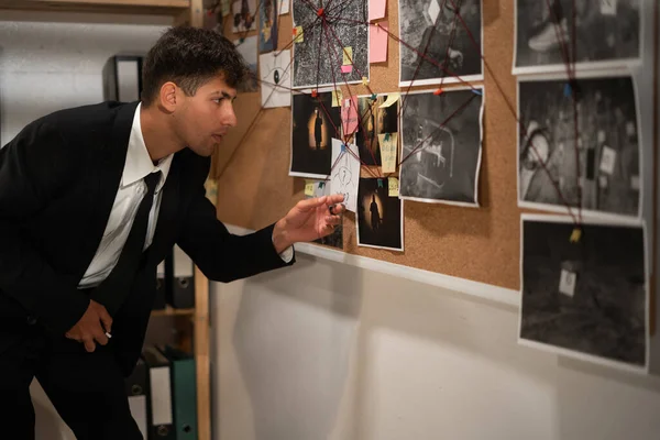 Young detective looking at evidence board in his office, copy space