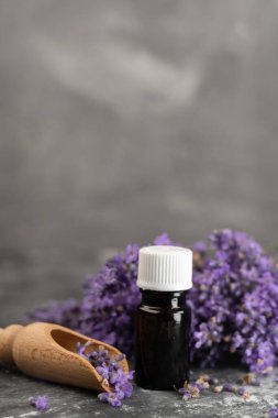 Ahşap kepçe üzerinde ahşap kepçe lavanta çiçekleri, aromaterapi spa masaj konsepti olan cam bir şişe lavanta yağı. Lavandula oleum