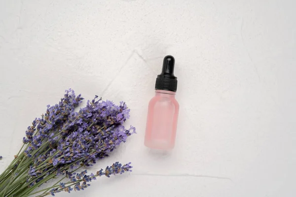 Natural oil in dripping bottle and lavender flowers isolated on white background. Cosmetic product. Aromatherapy. Flat lay , top view