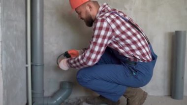 Tesisatçı yeni inşa edilen evin içinde PVC kanalizasyon boruları kuruyor. meslek, inşaat ve inşaat kavramı