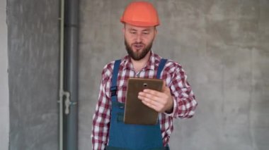 İnşaatçı ya da ustabaşının inşaat sahasında çalışırken video çağrısı vardır, proje aşamasını, inşaat, yenileme ve teknoloji konseptini kontrol etmek için tablet kullanan tamirci