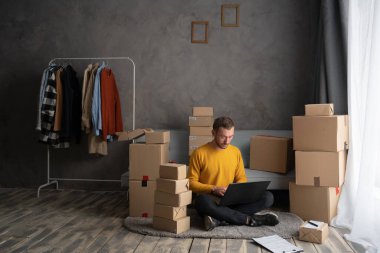 Erkek girişim küçük işletme sahibi ev ofisinde dizüstü bilgisayarla çalışıyor. Çevrimiçi kıyafet dükkanı. Çevrimiçi satış. E-ticaret, sme konsepti