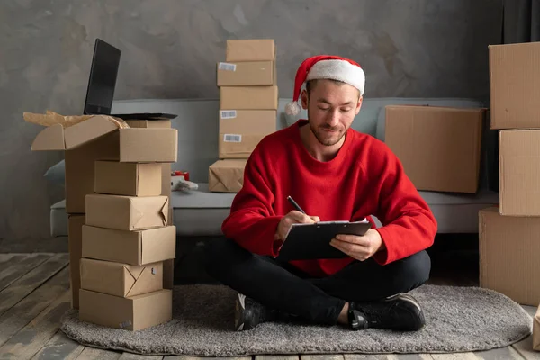 Happy young Santa in motion to deliver gifts on xmas eve packaging present sitting at home warehouse, fast speed express delivery, Merry Christmas rush concept.