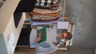 Küçük işletme sahibi kadın ev ofisinde çalışırken siparişleri kontrol ediyor, çevrimiçi giyim satıcısı bilgisayar kullanarak müşteri siparişlerini kontrol ediyor. KOBİ, e-ticaret ve tele pazarlama konsepti. Dikey video