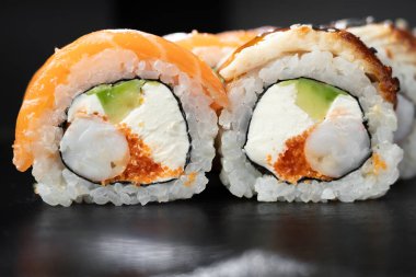 Philadelphia suşisi, somon, karides, avokado, krem peynir ve koyu taşlı arka plan. Suşi menüsü. Japon yemeği..